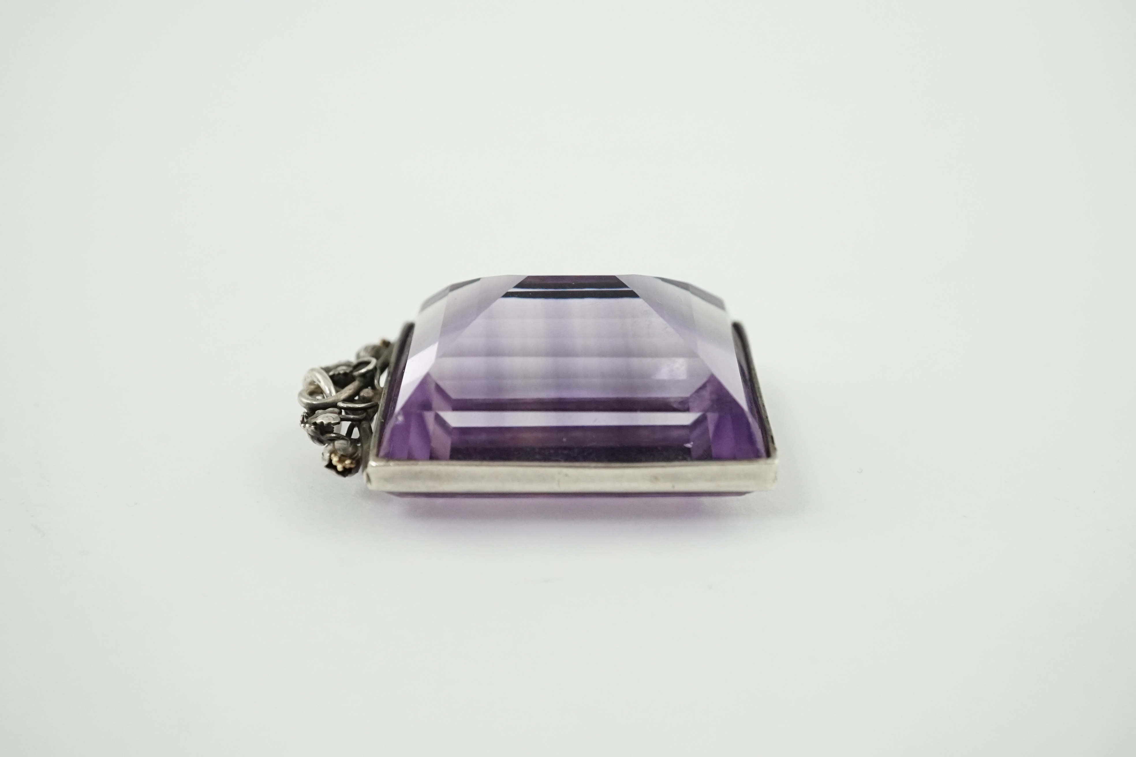 An Arts & Crafts silver mounted large rectangular cut amethyst set pendant